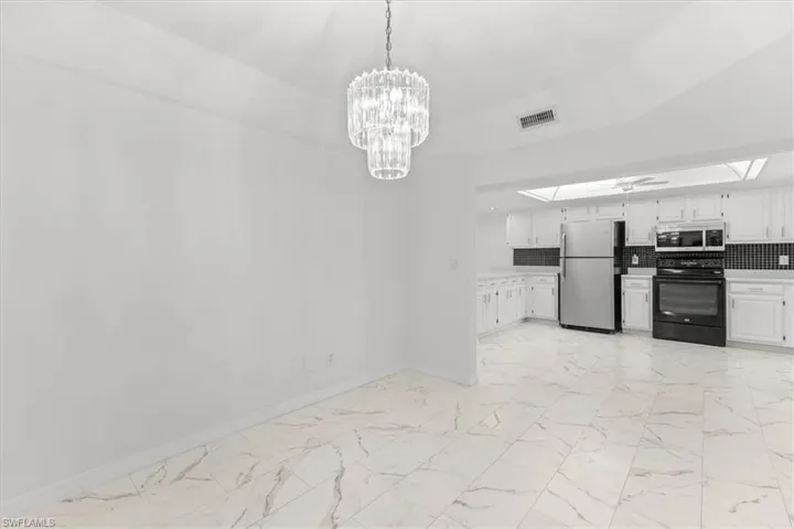 Kitchen with decorative backsplash, white cabinetry, appliances with stainless steel finishes, and light tile patterned floors