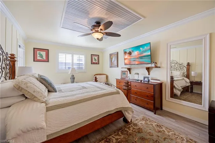 Bedroom with ceiling fan, light hardwood / wood-style floors, and ornamental molding