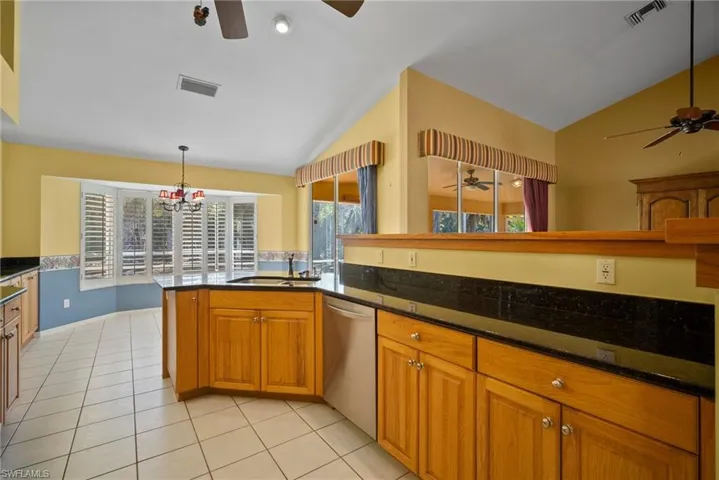 Kitchen featuring dishwasher, vaulted ceiling, a sink, and visible vents