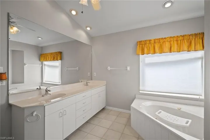 Bathroom with tile patterned flooring, a sink, and a ceiling fan