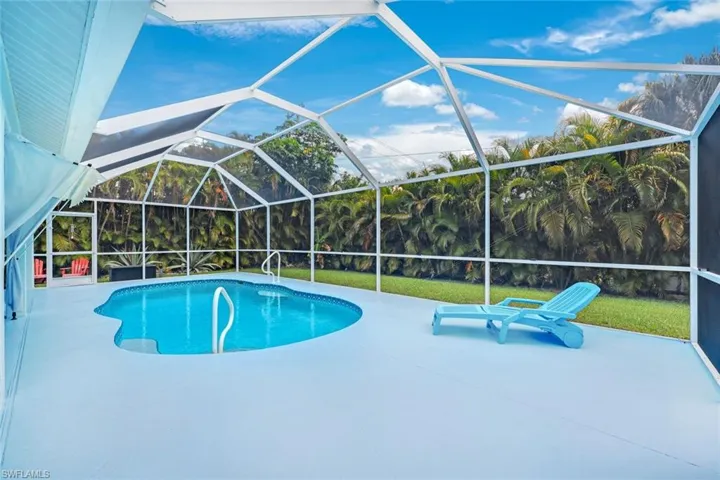 Outdoor pool with a sunroom, glass enclosure, and a patio area