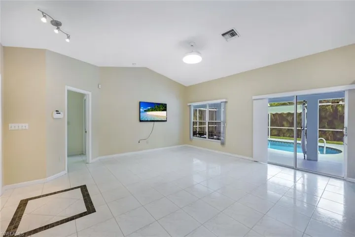 Spare room with vaulted ceiling, light tile patterned floors, and inlaid floor details