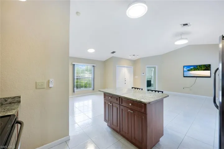 Kitchen with range, a center island, light stone counters, light tile patterned flooring, and freestanding refrigerator