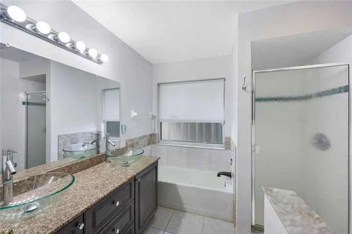 Bathroom with a garden tub, double vanity, and a stall shower