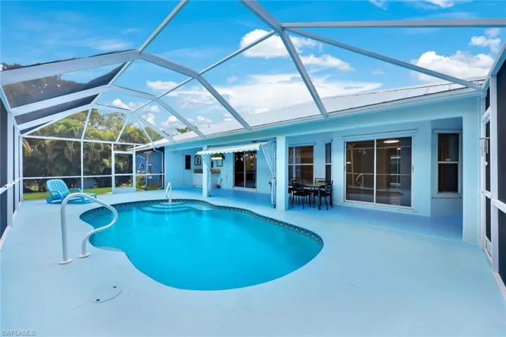 Swimming pool with a sunroom, glass enclosure, outdoor dining space, and a patio area