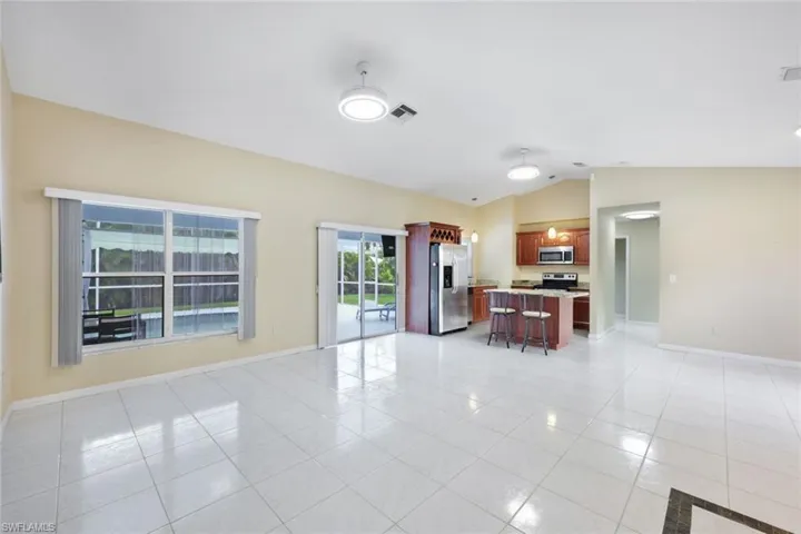 Living area with light tile patterned flooring and vaulted ceiling