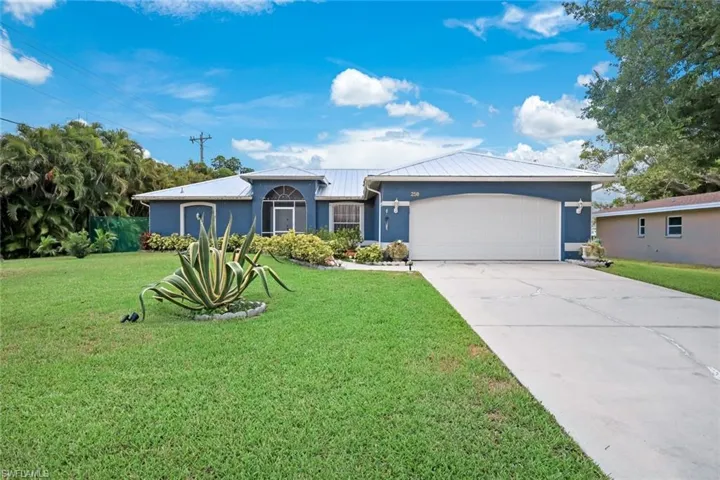 Ranch-style house featuring an attached garage, driveway, a front lawn, and stucco siding