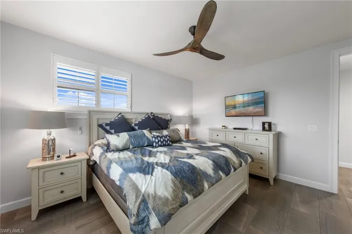 Spacious room featuring light wood-finish flooring, a ceiling fan, and window shutters