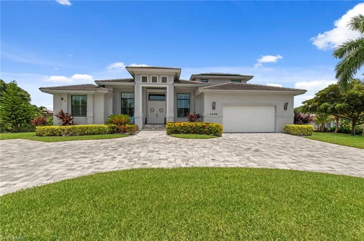 Contemporary exterior with a prominent portico entry, a paver driveway, an integrated garage, and manicured landscaping