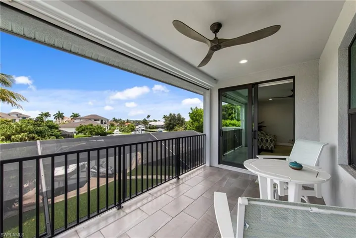 Covered balcony featuring tile flooring, a ceiling fan, and sliding glass doors
