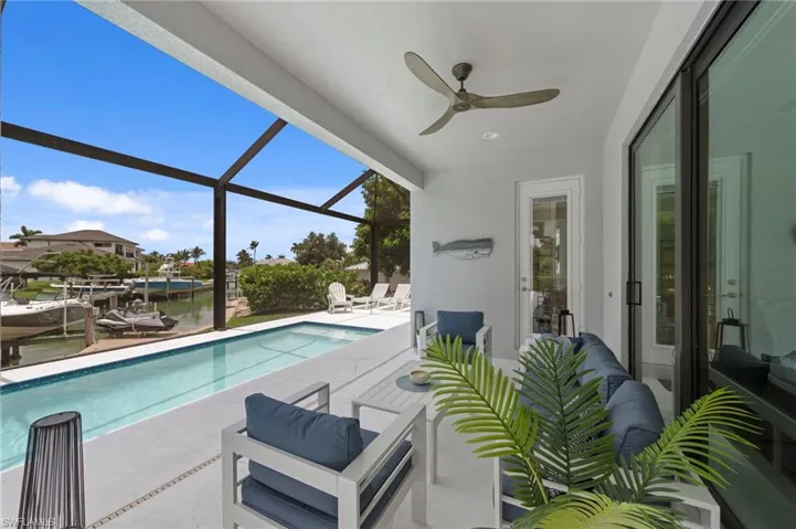 Screened lanai featuring a ceiling fan, direct pool access, and waterfront views
