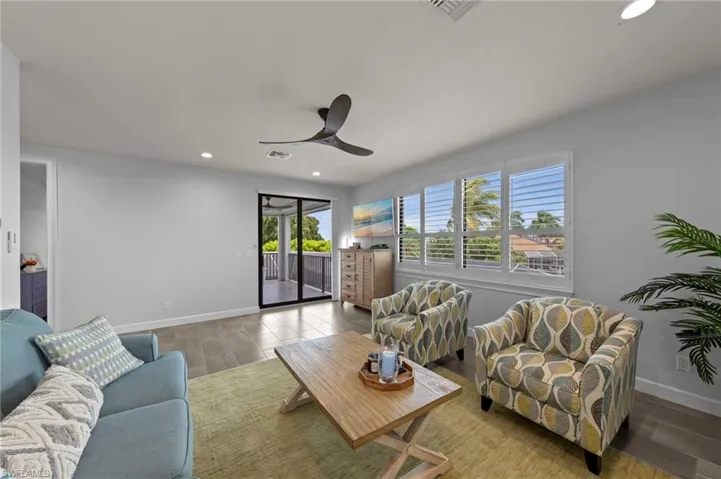 Living area featuring wood-finish flooring, recessed lighting, ceiling fan, and white plantation shutters