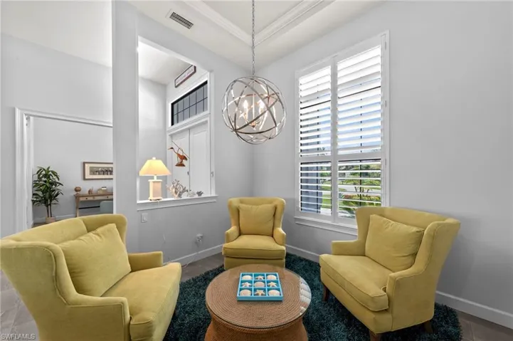 Living area featuring light gray walls, a tray ceiling, and a contemporary spherical chandelier
