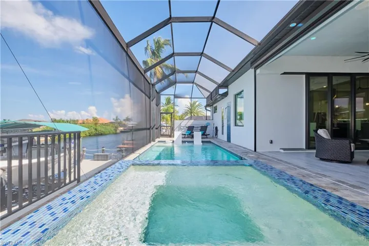 View of swimming pool with an in ground hot tub, a patio, and a lanai