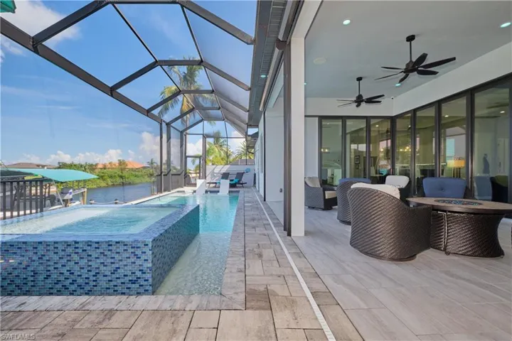 View of patio / terrace featuring ceiling fan, a swimming pool with hot tub, and glass enclosure