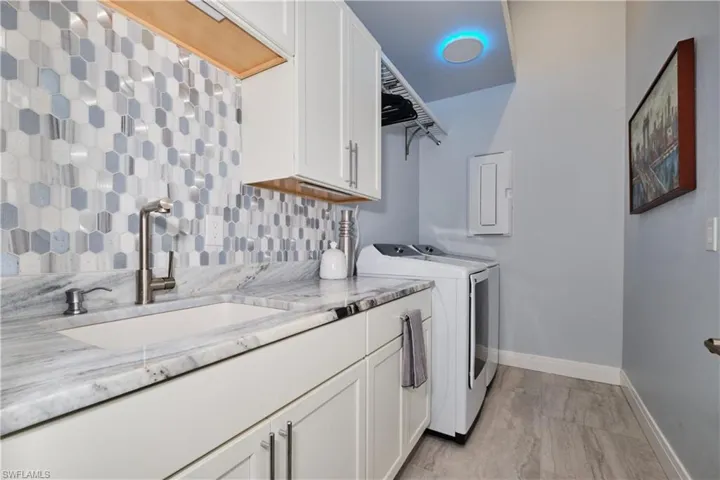 Laundry area featuring sink, independent washer and dryer, and cabinets