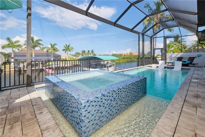 View of swimming pool with an in ground hot tub, a patio, and a lanai