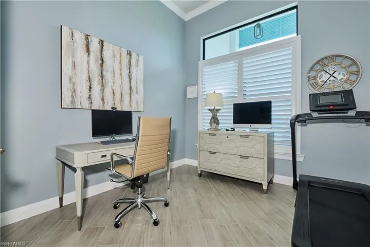 Home office with light hardwood / wood-style floors and ornamental molding
