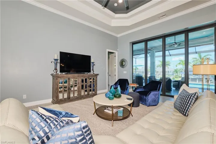 Living room with ceiling fan, crown molding, a high ceiling, and a tray ceiling