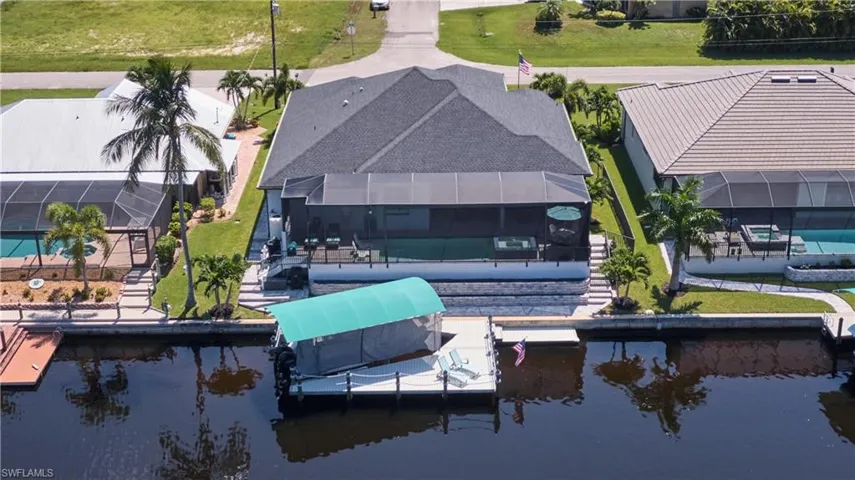 Dock area featuring glass enclosure, a swimming pool, a lawn, and a water view