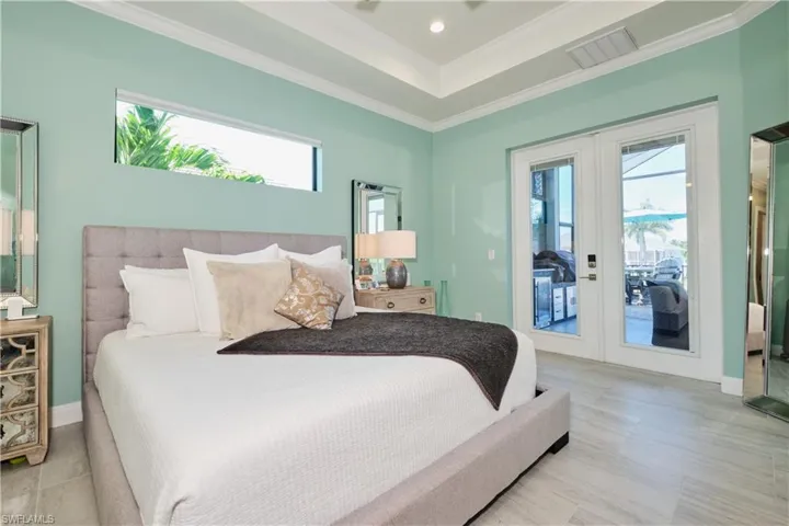 Bedroom featuring access to outside, french doors, crown molding, and a tray ceiling