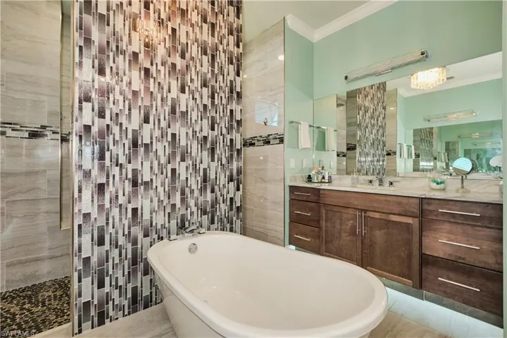 Bathroom with vanity, crown molding, tile patterned floors, independent shower and bath, and tile walls