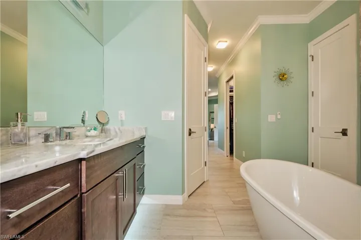 Tiled bedroom featuring ceiling fan, crown molding, and a tray ceiling