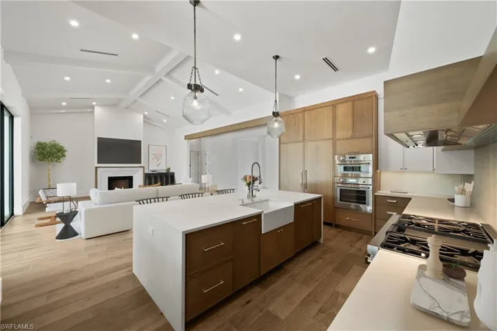 Kitchen featuring sink, lofted ceiling with beams, a spacious island, wood-type flooring, and appliances with stainless steel finishes
