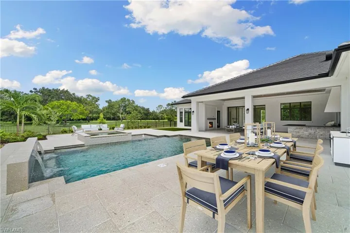 View of swimming pool with an in ground hot tub, pool water feature, a patio, and an outdoor kitchen