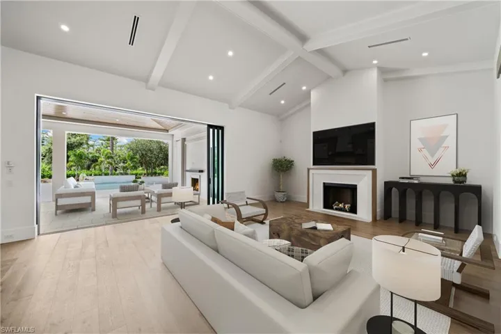 Living room featuring beam ceiling, high vaulted ceiling, and light wood-type flooring