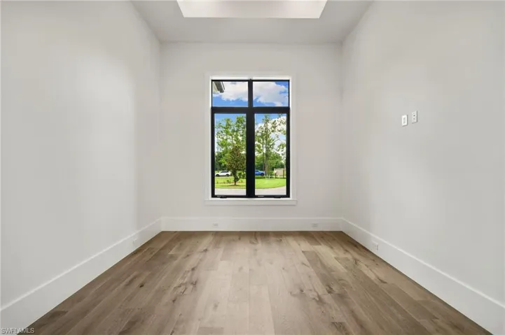 Spare room with a skylight and light hardwood / wood-style flooring