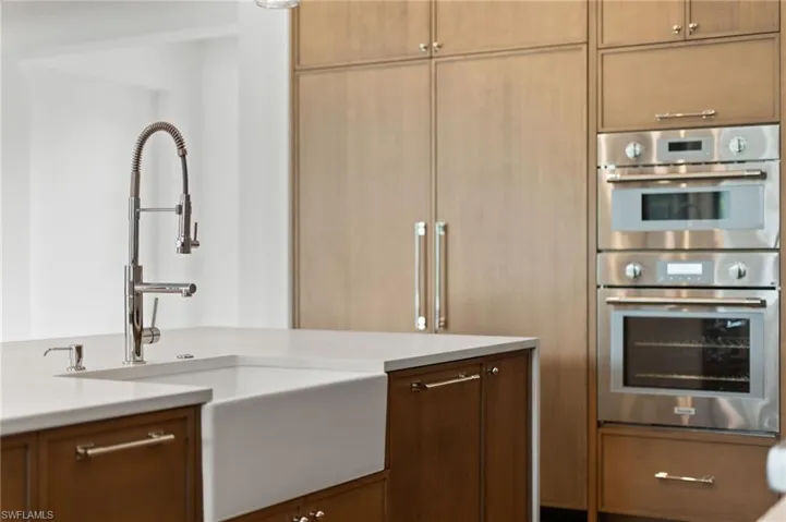 Kitchen featuring light brown cabinetry, sink, and double oven