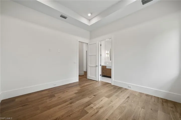 Unfurnished bedroom featuring connected bathroom and light wood-type flooring