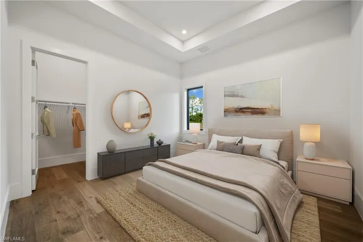 Bedroom with a tray ceiling, a closet, and hardwood / wood-style floors