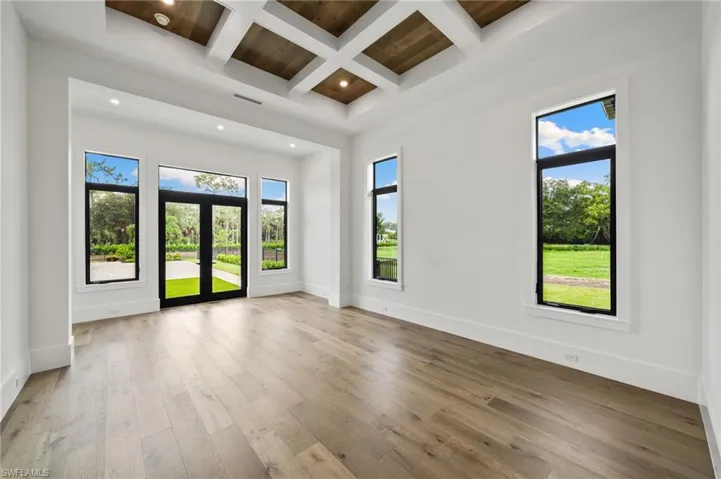 Spare room featuring light hardwood / wood-style floors, coffered ceiling, and beamed ceiling