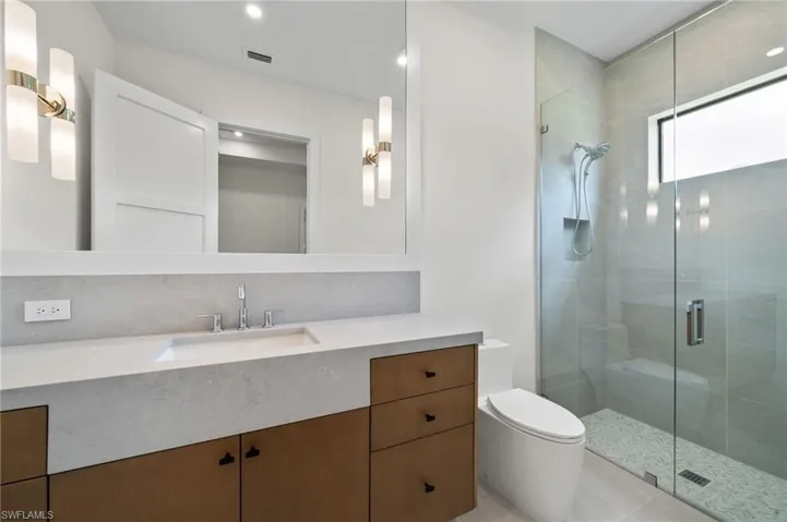 Bathroom featuring tile patterned floors, a shower with shower door, toilet, and vanity