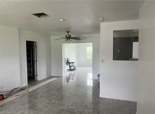 Spacious interior with neutral white walls and reflective grey tile flooring