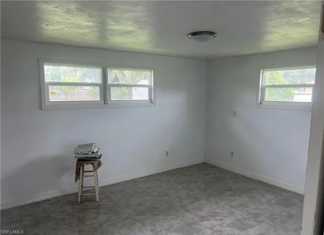 Bright room featuring white walls, multiple windows, and a flush-mount ceiling light fixture