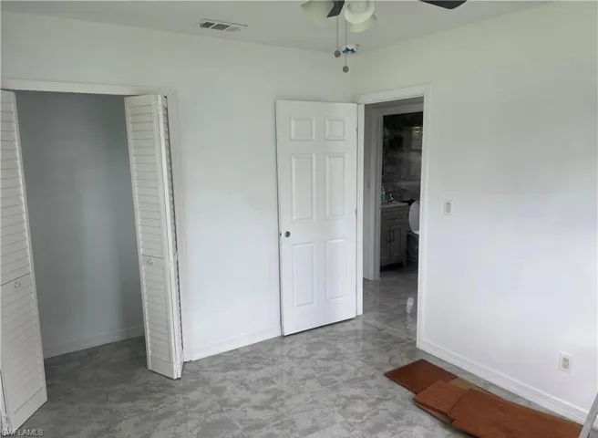 Interior space featuring light gray patterned tile flooring, white painted walls, and a ceiling fan