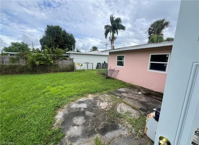 Expansive rear yard featuring a grass lawn, privacy fencing, and mature perimeter trees