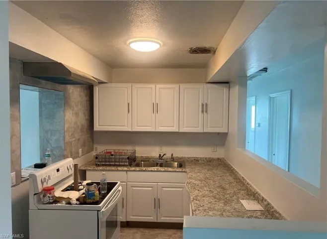 Kitchen featuring white cabinetry, a double basin stainless steel sink, and granite-look countertops