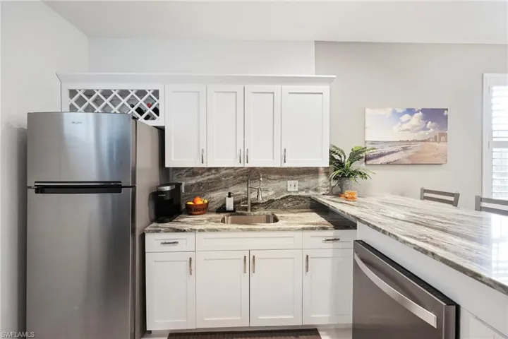 Kitchen with backsplash, sink, white cabinets, and appliances with stainless steel finishes
