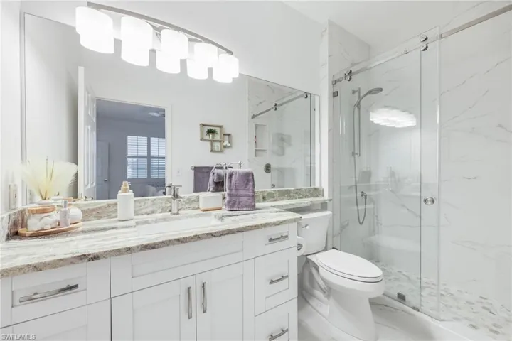Bathroom featuring vanity, toilet, and an enclosed shower