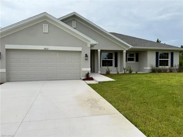 Modern single-story residence featuring a two-car garage, grey stucco exterior, dark blue window shutters, and a concrete driveway