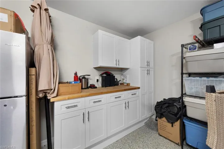 Garage workbench with white cabinets, butcher block counters, epoxy floors, garage door screen