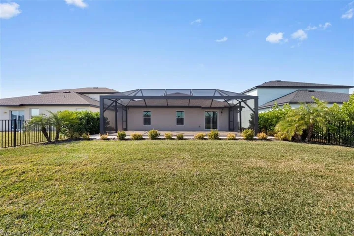 Back of house with screen enclosure and a landscape.