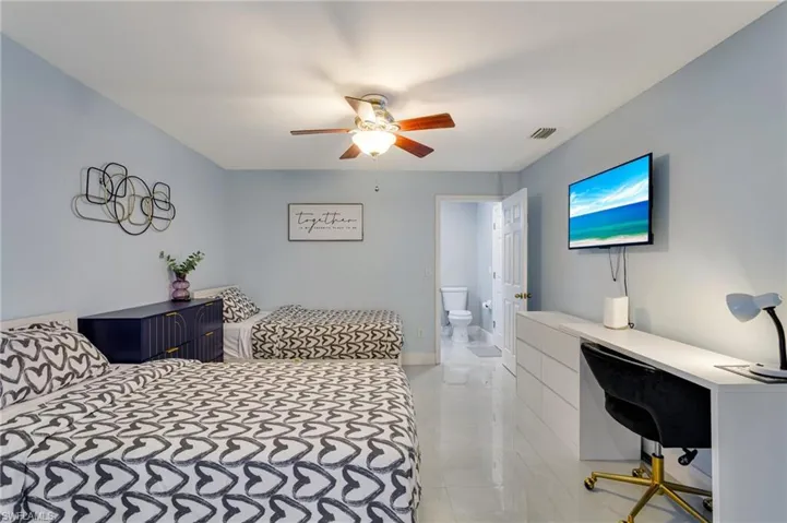 Bedroom featuring light tile patterned floors, visible vents, ensuite bathroom, and ceiling fan