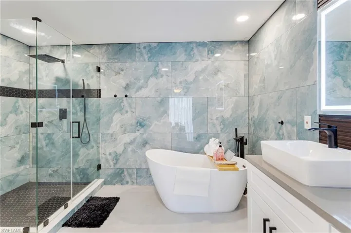 Full bath featuring a freestanding tub, vanity, tile walls, and a stall shower