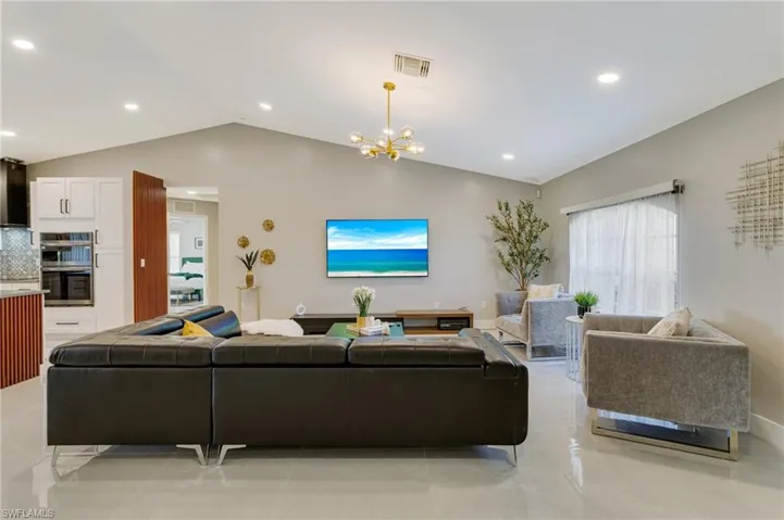 Living room featuring visible vents, vaulted ceiling, a chandelier, recessed lighting, and light tile patterned flooring