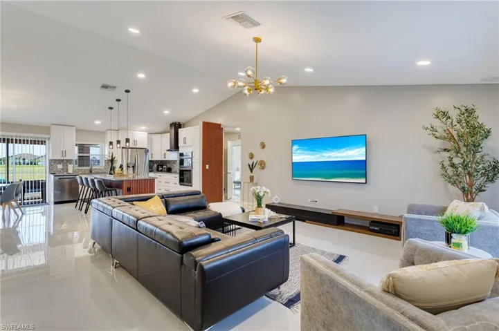 Living room with recessed lighting, visible vents, vaulted ceiling, and an inviting chandelier